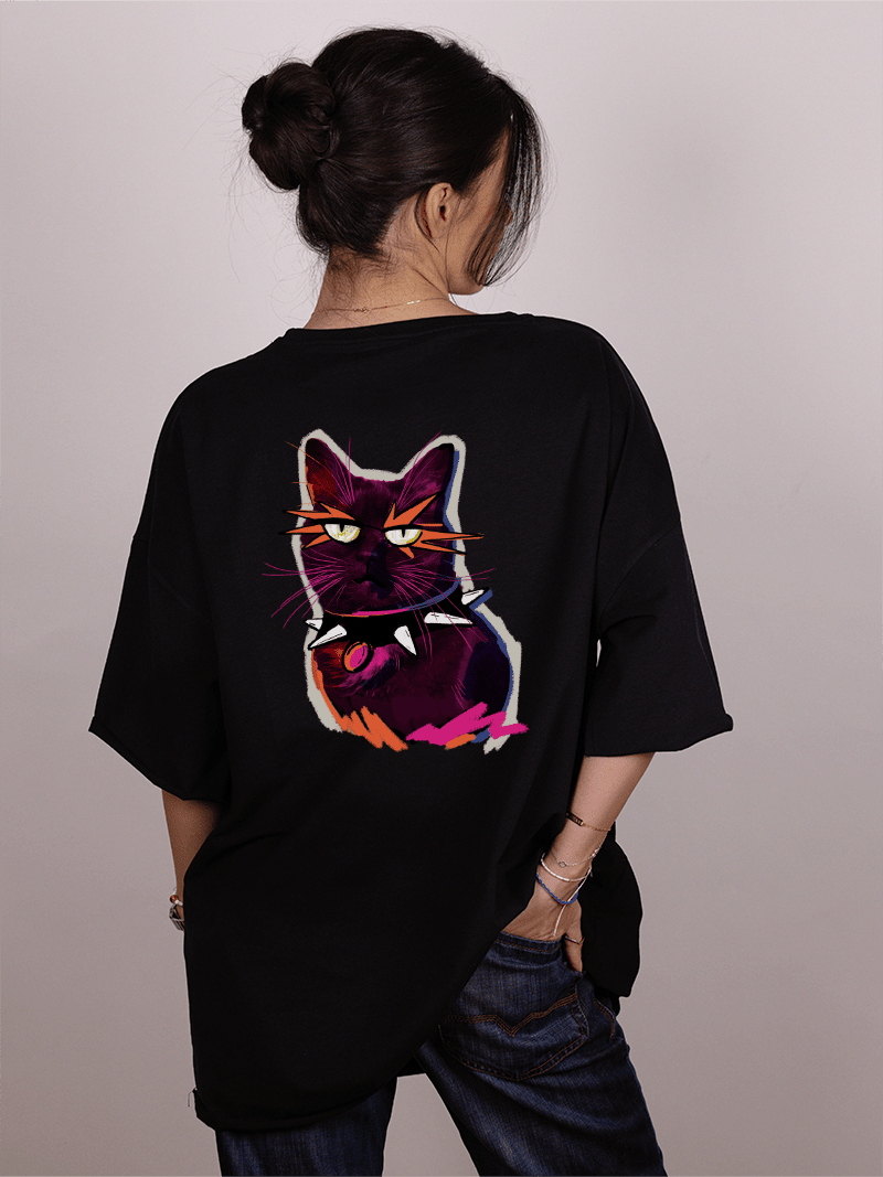 Girl wearing a black "Ivica i Majicat-shirt with a colorful cat graphic on the back against a plain background