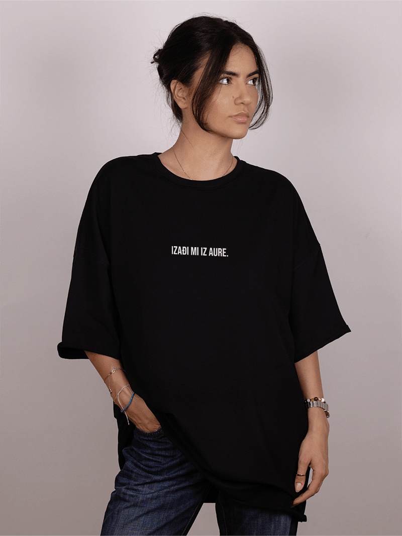 Girl wearing a black oversized "ivica i Majica" t-shirt with text on a plain background