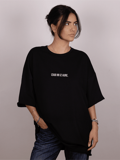 Girl wearing a black oversized "ivica i Majica" t-shirt with text on a plain background